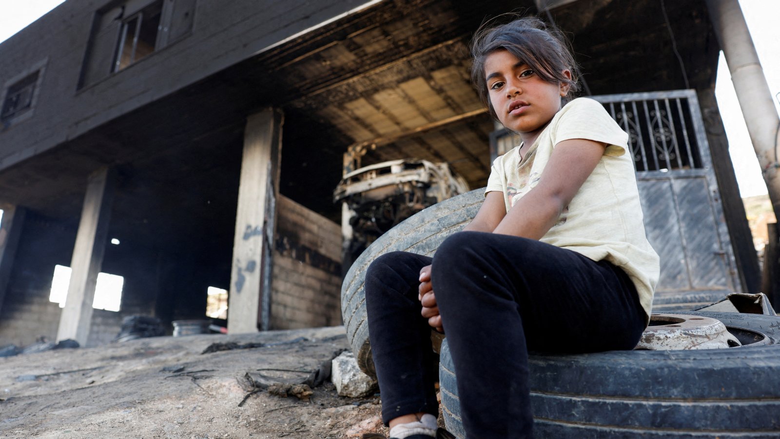 A Palestinian girl sits in front of her house after Israeli settlers attacked the village of al-Mughayyer, in the Israeli-occupied West Bank, April 17, 2024. REUTERS/Mohammed Torokman