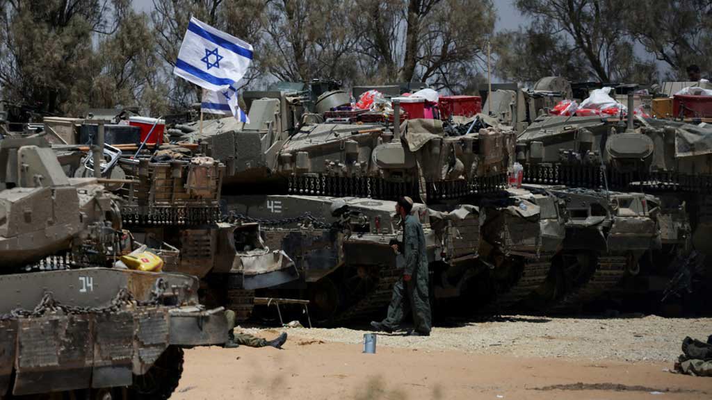An Israeli soldier walks near military vehicles, amid the ongoing conflict between Israel and the Palestinian Islamist group Hamas, near Israel's border with Gaza in southern Israel, May 29, 2024. REUTERS