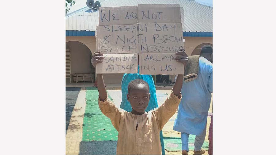 A boy holds a sign to protest against, what a teacher, local councilor and parents said, the kidnapping of hundreds school pupils by gunmen after the Friday prayer in Kaduna, Nigeria March 8, 2024. REUTERS/Stringer/File Photo